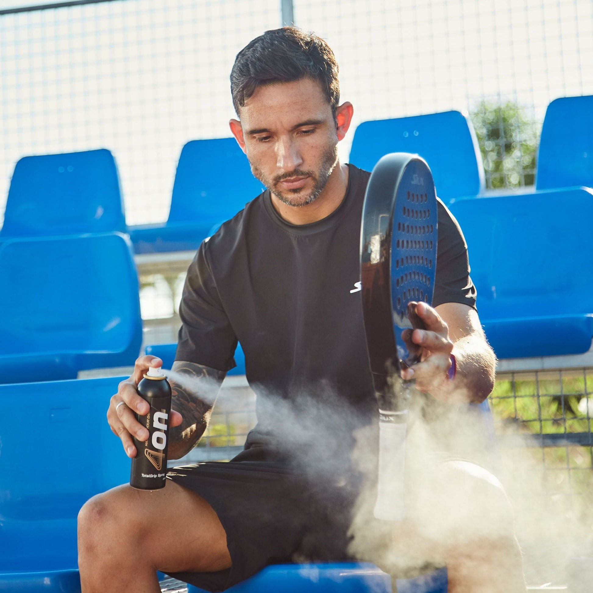 Applying 4on TotalGrip Spray to padel racket handle - improves grip and control during play